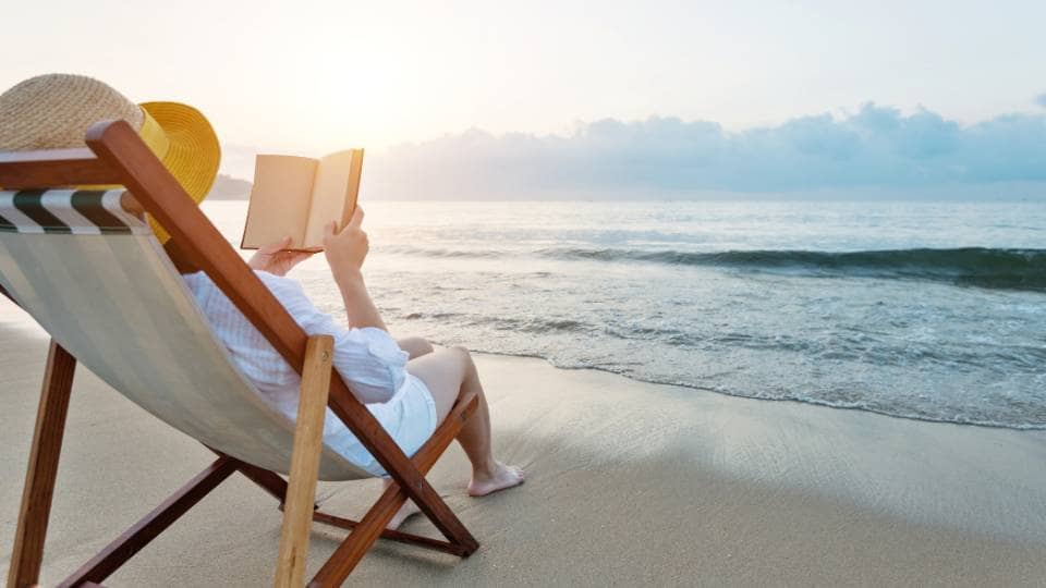 woman relaxing reading a book at the beach prepare skincare self-care