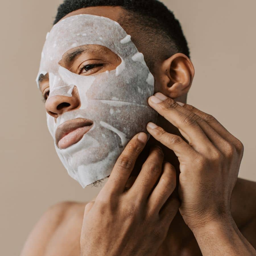 Guy applying sheet mask to hydrate skin routine