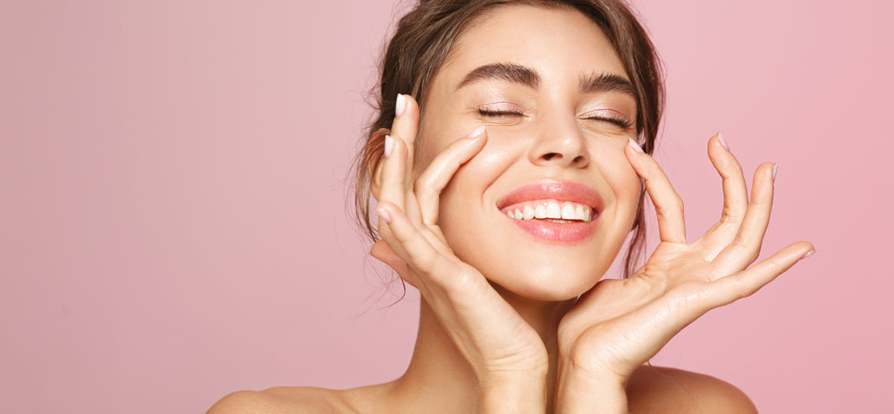 Smiling woman with glowing skin in front of pink background