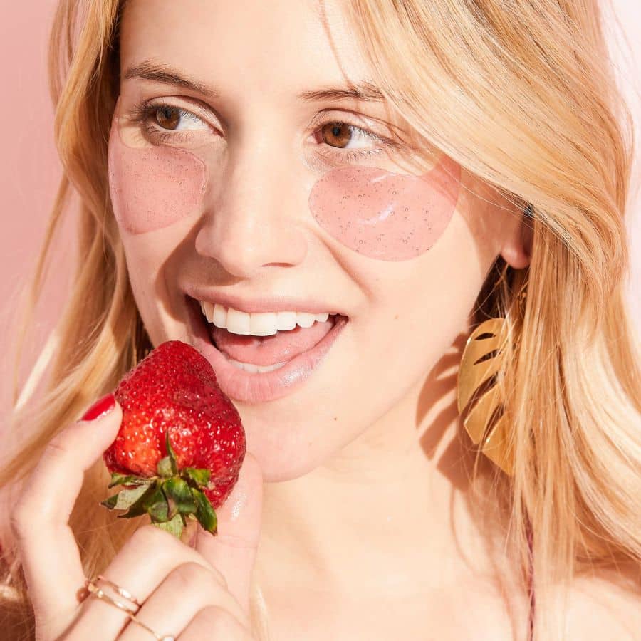 Woman eating strawberry wearing rose eye gels