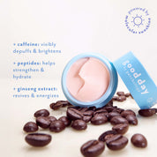 A cosmetic cream jar with a light blue lid lies on its side on a white background, surrounded by scattered coffee beans. The cream inside is a pale pink.