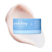 A light blue cosmetic jar labeled 'good day eye pillow 360° brightening' centered over a large pale pink cream smear on a solid green background.