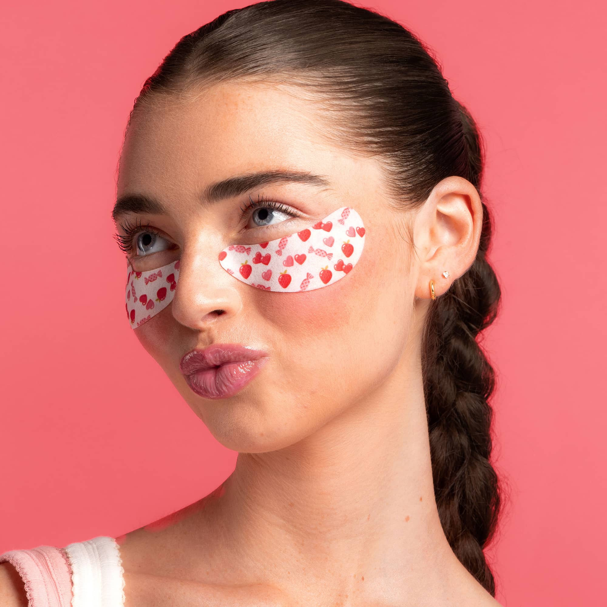 Woman with red heart eye patches on a pink background