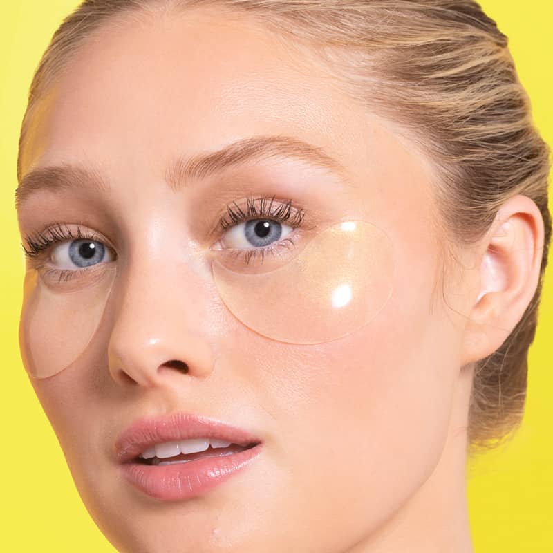 Woman wearing eye patches against a yellow background