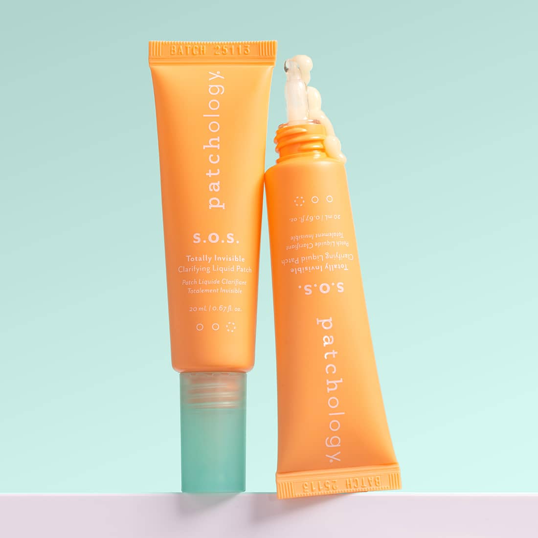 Two orange SOS bottles of Patchology skincare products on a light blue and pink gradient background