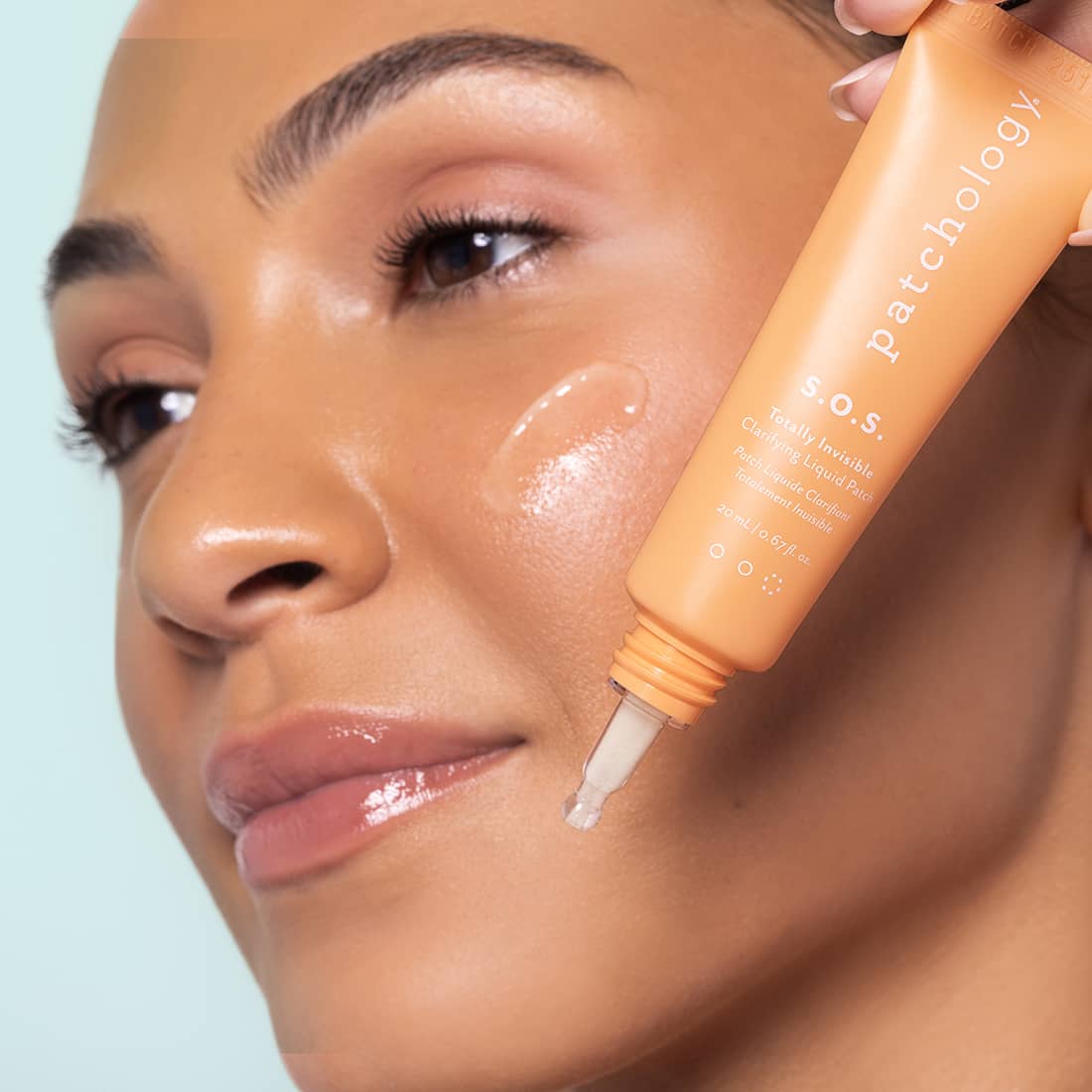 Person applying a skincare product to their face with a focus on the brand 'Patchology'.