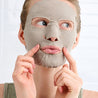 Person applying a Detox Smartmud facial mask on a white background