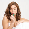 Model with reddish brown hair looking down at the Little Helpers® Supplement Strip: Calm in her right hand and raising it up to her mouth