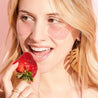 woman with blonde hair eating a strawberry with rosé eye gels